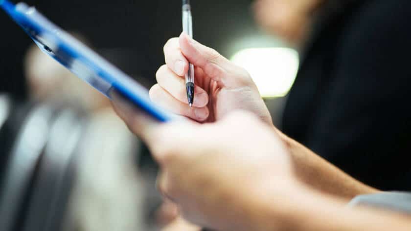 Image of a duty holder using a clipboard to make notes about an asbestos register.