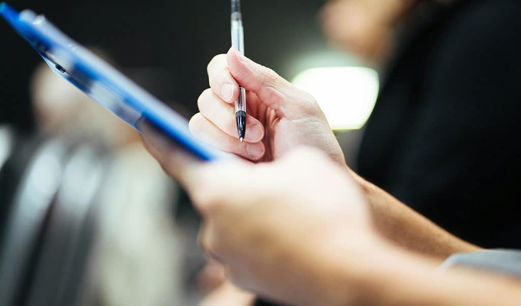 Image of a duty holder using a clipboard to make notes about an asbestos register.